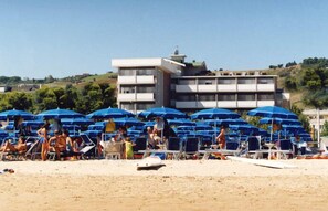 A beach with rows of blue umbrellas and lounge chairs. - Palmarosa (Roseto degli Abruzzi)