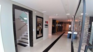 A modern hotel corridor with a staircase, a large mirror, and a black and white floor design. - Hotel Avalon Maringá (Maringá)