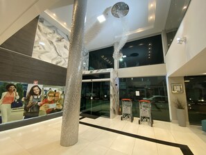 A modern interior with a central column, glass doors, and a marble wall. - Hotel Avalon Maringá (Maringá)