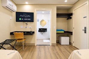 A hotel room with a desk, chair, TV, and a small kitchenette. - Hotel Avalon Maringá (Maringá)