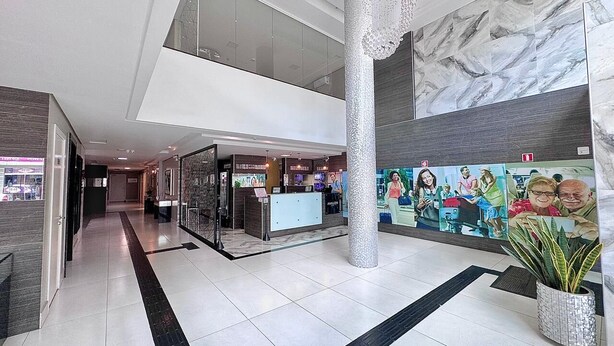 A modern hotel lobby with a reception desk, a large pillar, and a mural on the wall. - Hotel Avalon Maringá (Maringá)