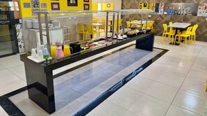 A buffet area with a glass partition, yellow chairs, and a variety of food items. - Hotel Avalon Maringá (Maringá)