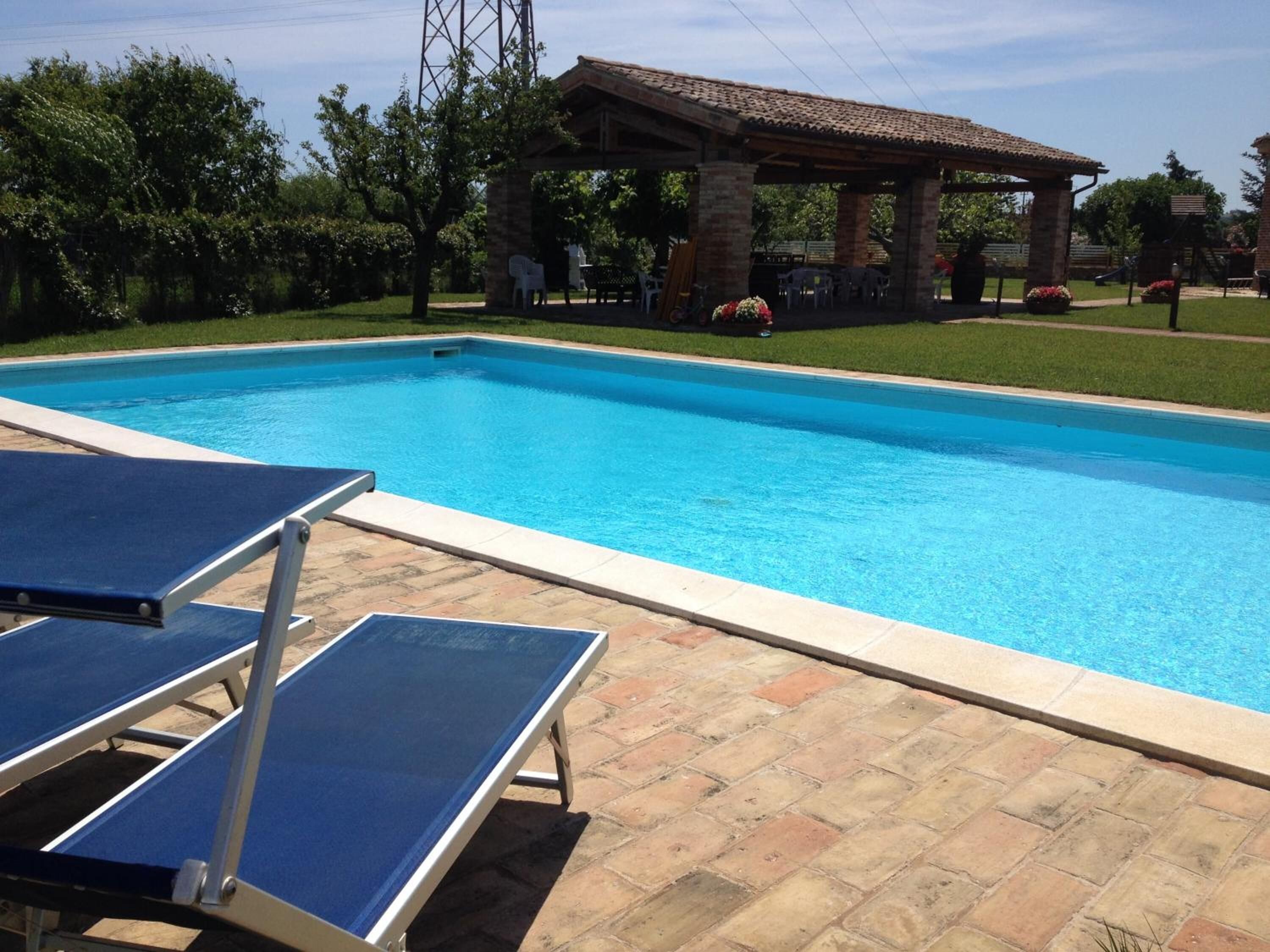 Une piscine avec des chaises longues et un kiosque en arrière-plan.