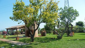 Un espacio cubierto de césped con un edificio de ladrillo, un árbol y un parque infantil.