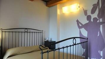 A bedroom with a metal bed frame, a beige mattress, a nightstand, and a wall-mounted light fixture.