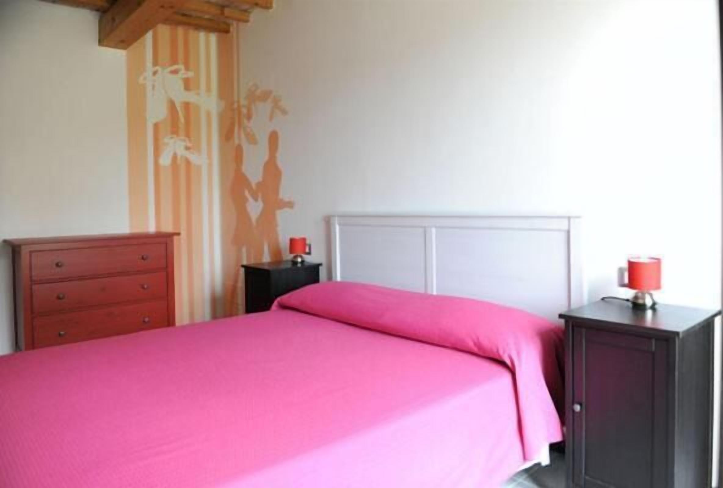 A bedroom with a bed, a dresser, a nightstand, and a cabinet.