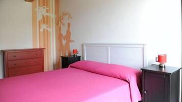 A bedroom with a bed, a dresser, a nightstand, and a cabinet.