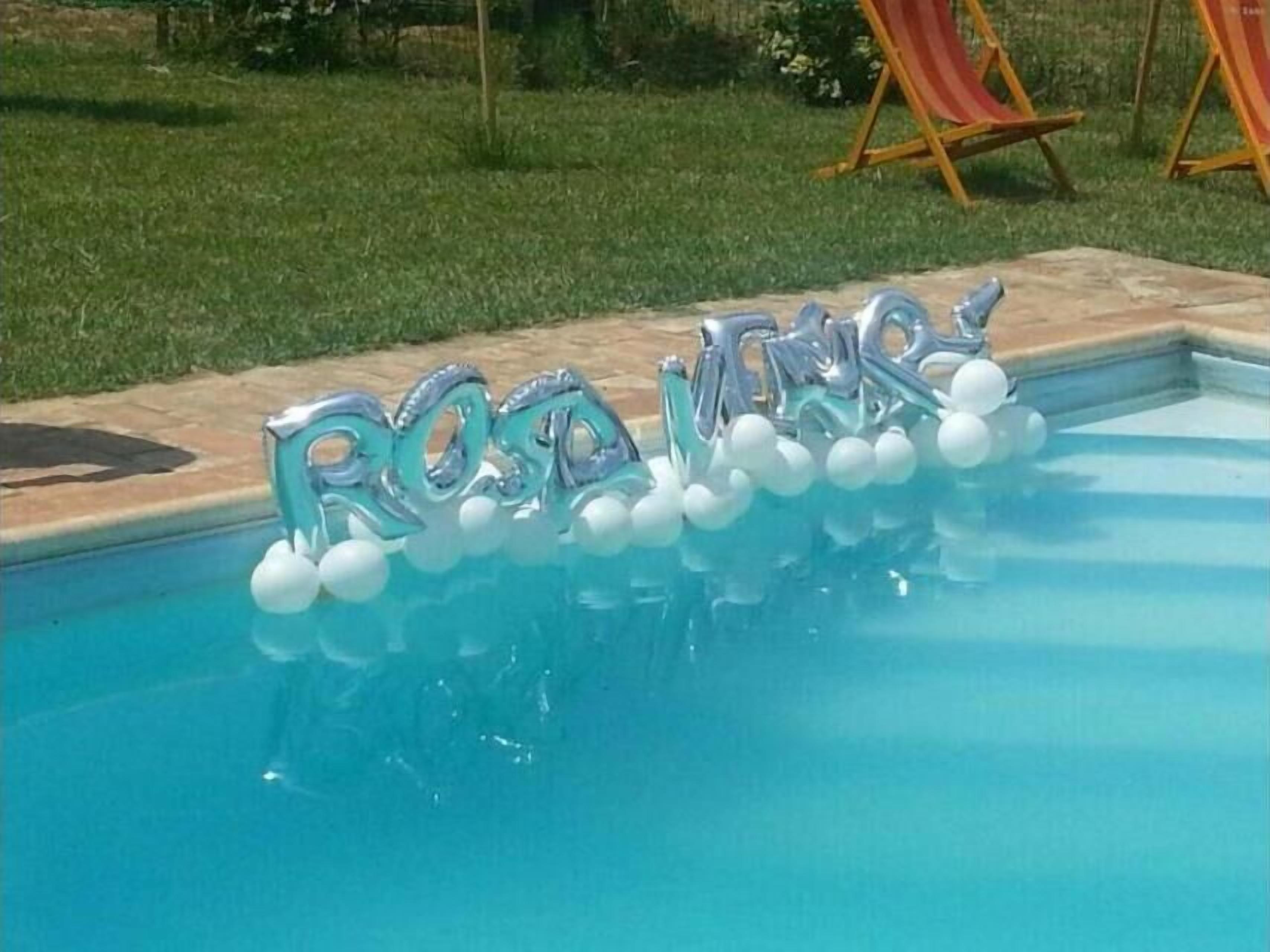 Zwembad met metalen letters waarop ‘RODNEY’ staat en witte ballonnen.
