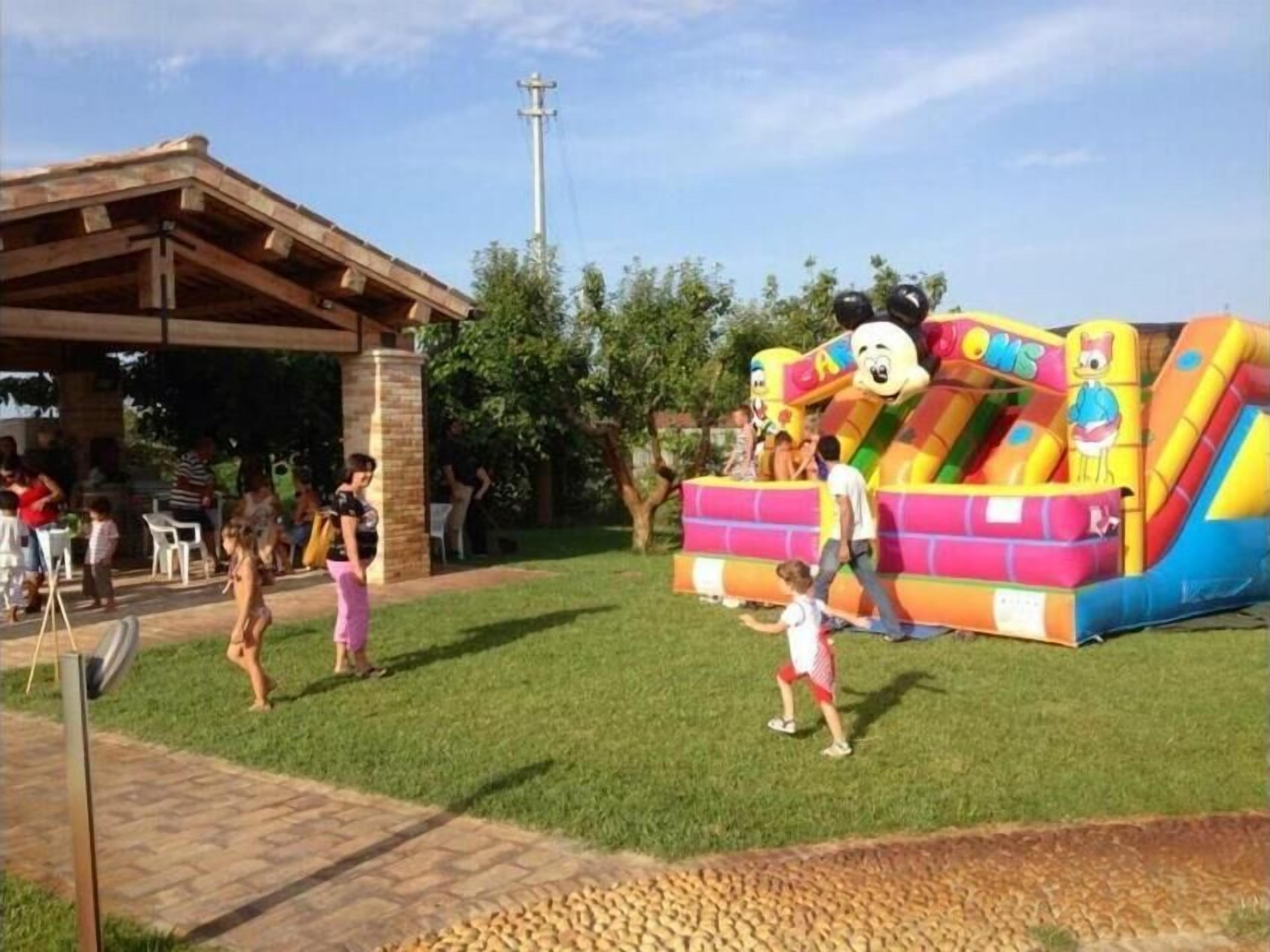 A grassy area with a colorful inflatable play structure and a covered pavilion.