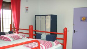 Una habitación tipo dormitorio con dos camas, un armario y una puerta.