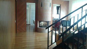 A spacious living room with a wooden floor, a fireplace, and a staircase with a black railing. - B&B Paradiso (Loreto)