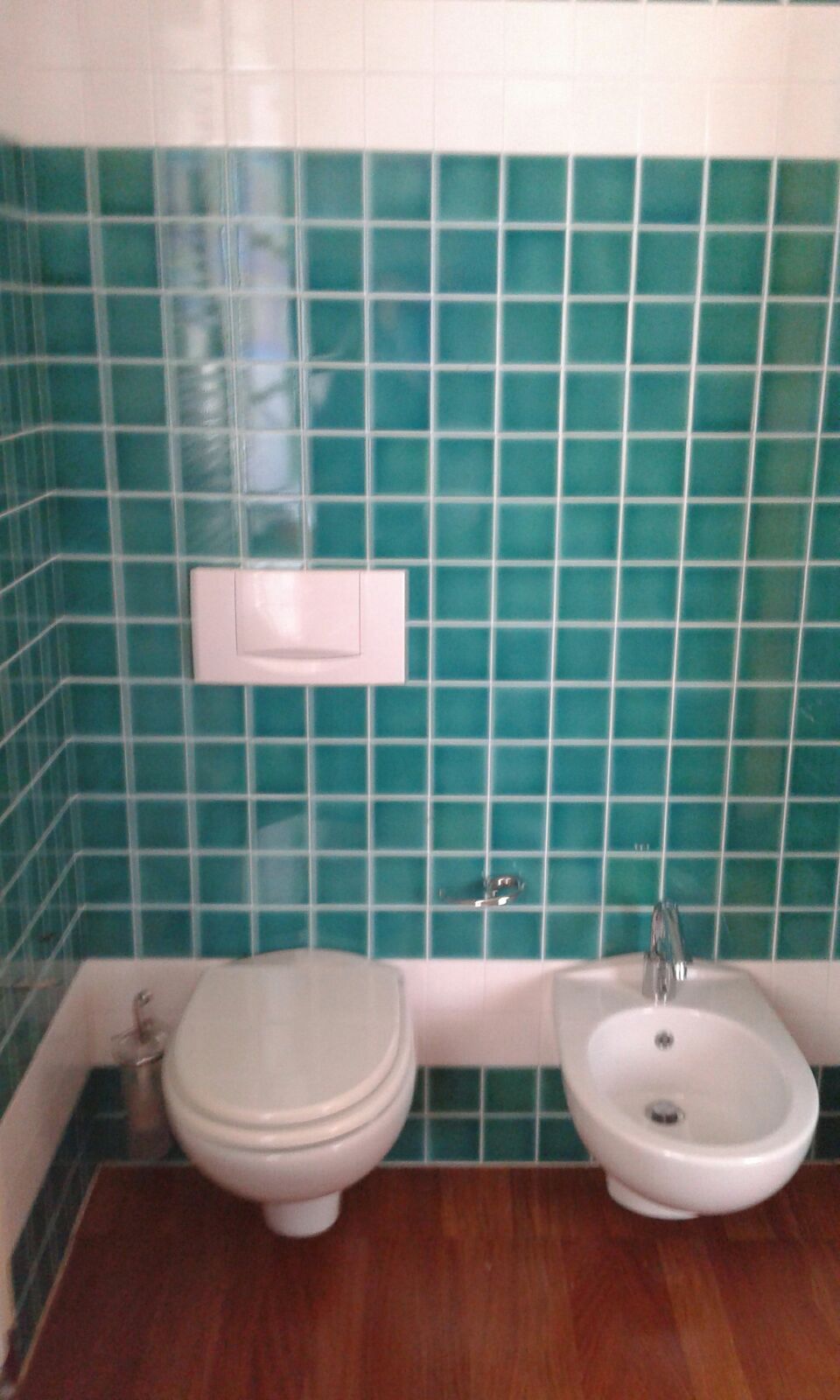 Ein Badezimmer mit Toilette, Bidet und einem wandmontierten Waschbecken.