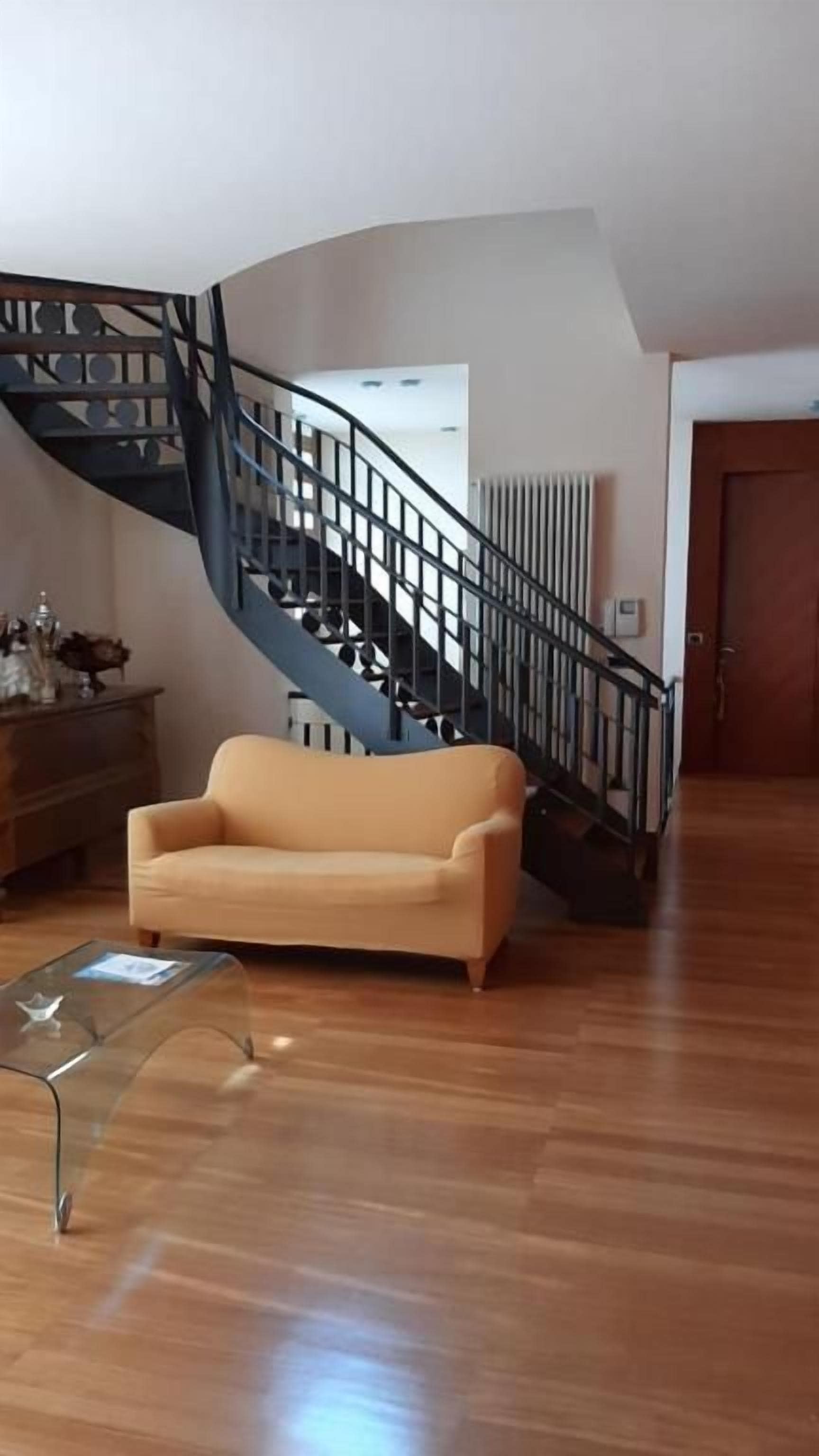 A living room with a curved staircase, a sofa, and a coffee table.