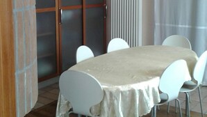 A dining area with a table covered by a tablecloth, surrounded by white chairs. - B&B Paradiso (Loreto)