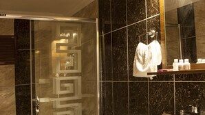 Un baño moderno con ducha envuelta en vidrio, inodoro blanco y tocador con espejo.
