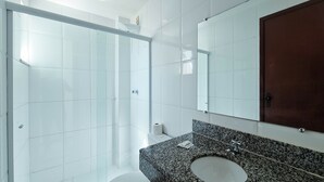A modern bathroom with a glass shower enclosure, a granite countertop sink, and a large mirror. - Pousada Praia do Flamengo (Salvador)