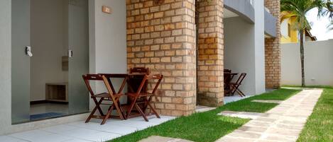 A modern building with a brick column, a paved pathway, and outdoor furniture.