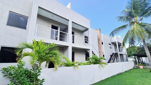 A modern multi-story building with balconies, a brick column, and a palm tree in the foreground. - Pousada Praia do Flamengo (Salvador)