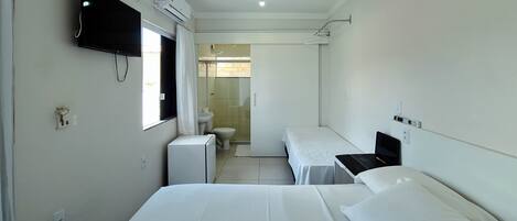 Una habitación de hotel con dos camas, televisión, un escritorio pequeño y zona de ducha.