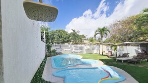 A backyard with a small inflatable pool, a hose, and a white fence. - Pousada Praia do Flamengo (Salvador)