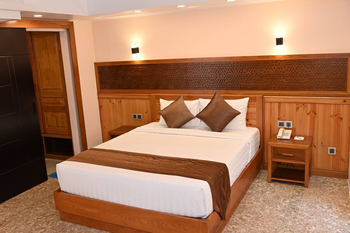 Ein Hotelzimmer mit einem hölzernen Bett, Nachttischen und einem Telefon.