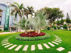 A landscaped garden with palm trees, a central flower bed, and a paved walkway. - Tran Chau Beach & Resort (Ho Chi Minh City)