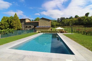 A rectangular swimming pool with a stone deck, surrounded by a fenced yard with a grassy area and a small garden. - Stunning Private Villa for 4 Guests With Wifi, Private Pool, TV, Veranda, Pets Allowed and Parking (Arezzo)