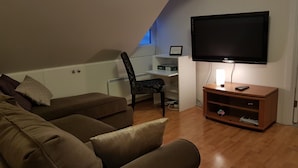 A living room with a sofa, a chair, a TV, and a wooden entertainment unit.