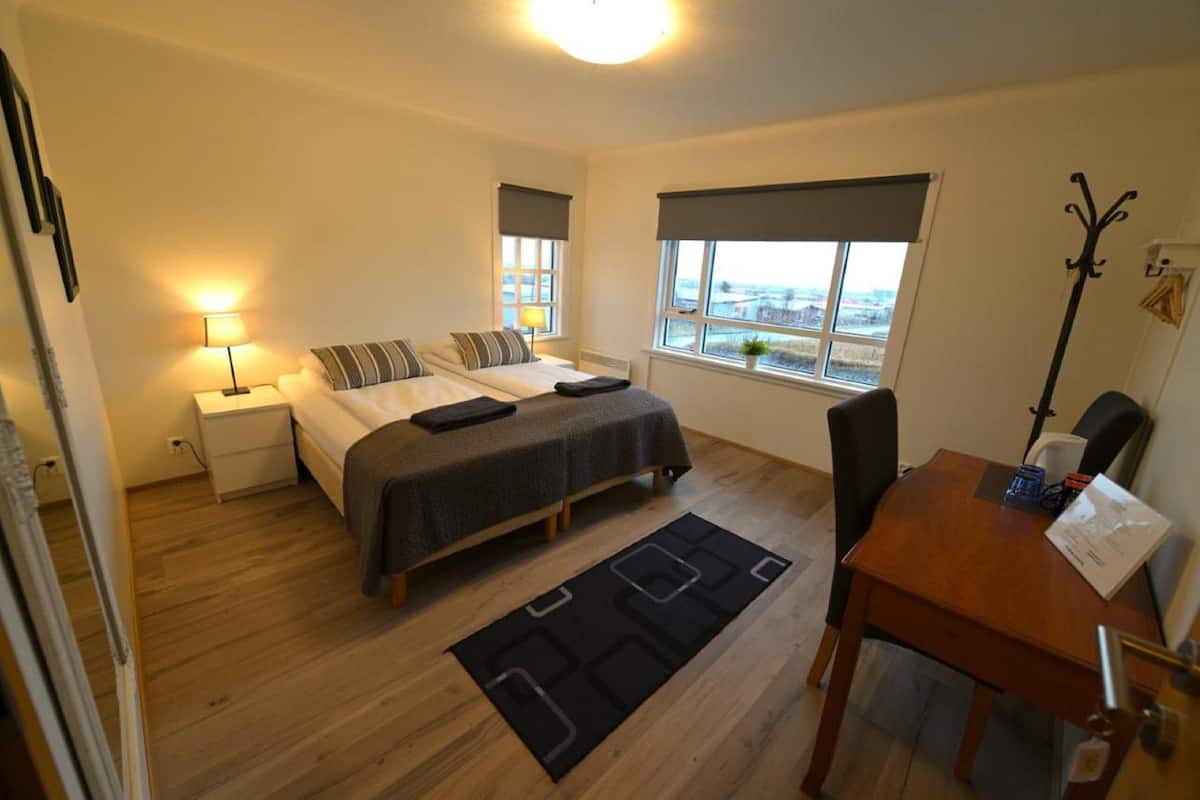 Une chambre à coucher avec un lit, des tables de chevet, un bureau et une chaise.