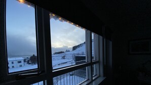 A room with a large window overlooking a snowy landscape, including a building and trees.