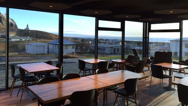 A modern dining area with large windows offering a view of a coastal landscape.