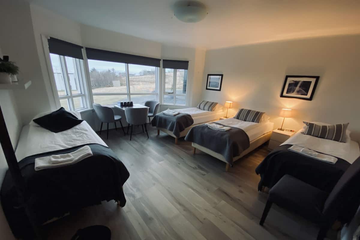 Une chambre d’hôtel avec deux lits, un bureau, des chaises et de grandes fenêtres.