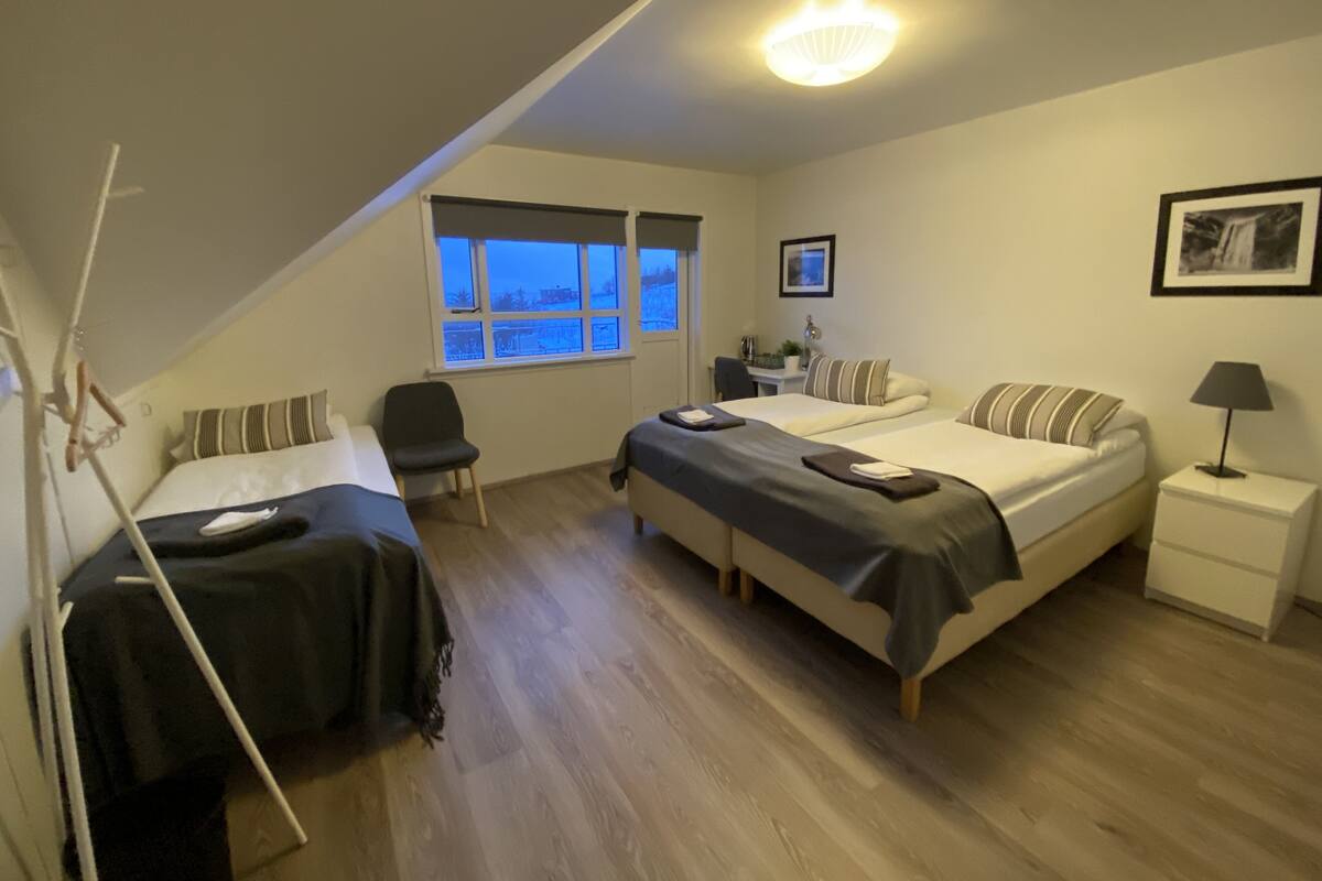 Une chambre avec deux lits, un bureau, une chaise et une fenêtre donnant sur un beau paysage.