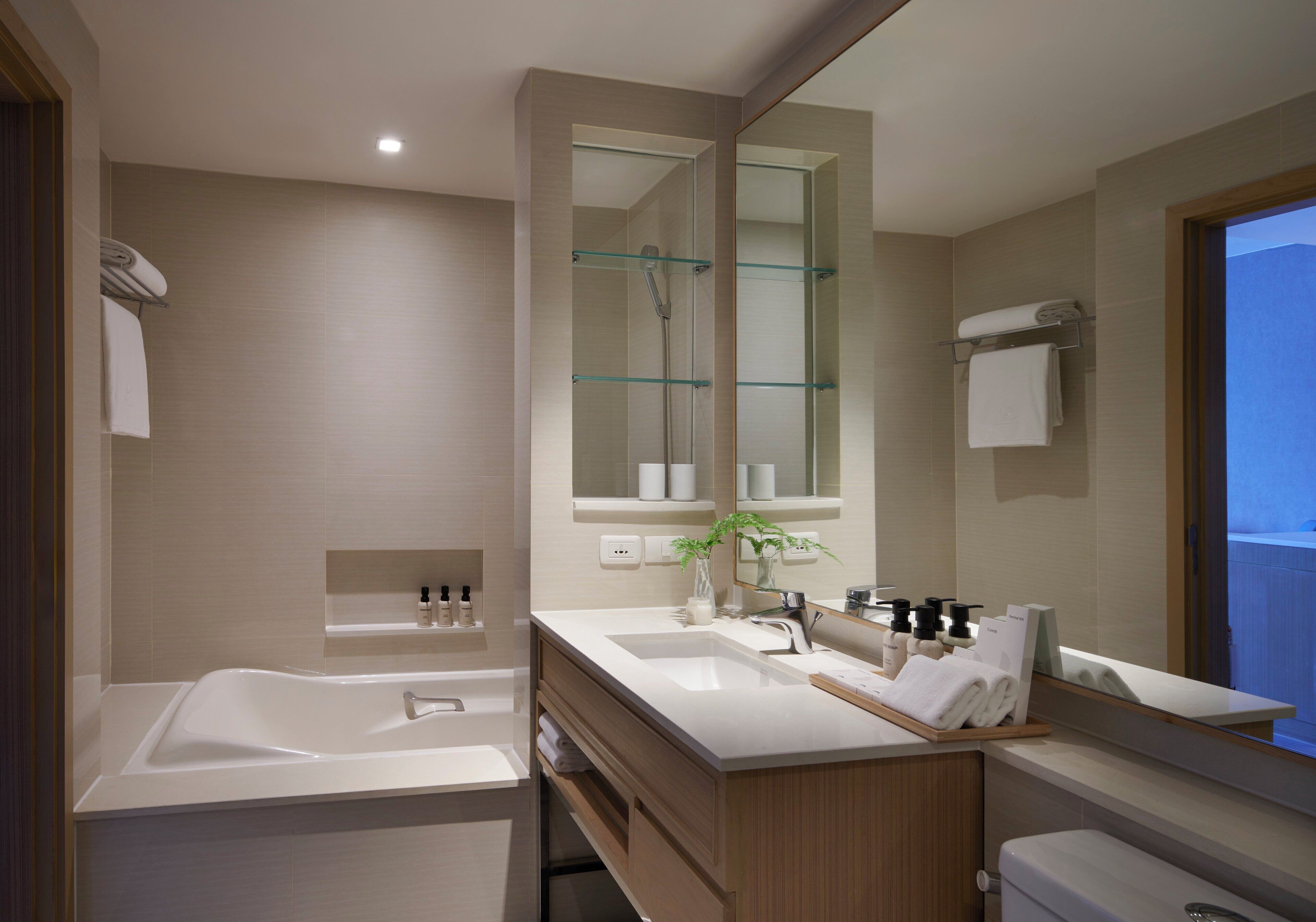 A modern bathroom with a large bathtub, a double sink vanity, and a large mirror.