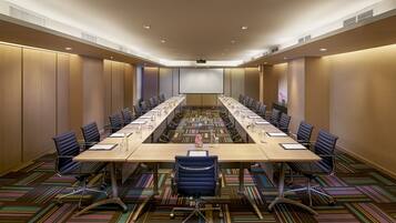 Une salle de conférence équipée d’une longue table, de nombreuses chaises et d’un écran de projection.