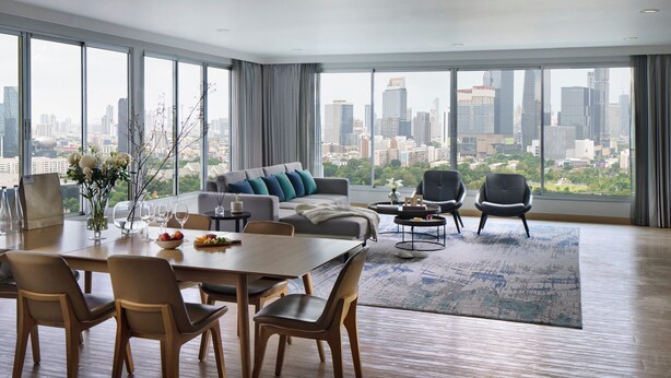 Un salon moderne avec un coin repas, de grandes fenêtres offrant une vue sur la ville et un panorama urbain visible à travers ces fenêtres.