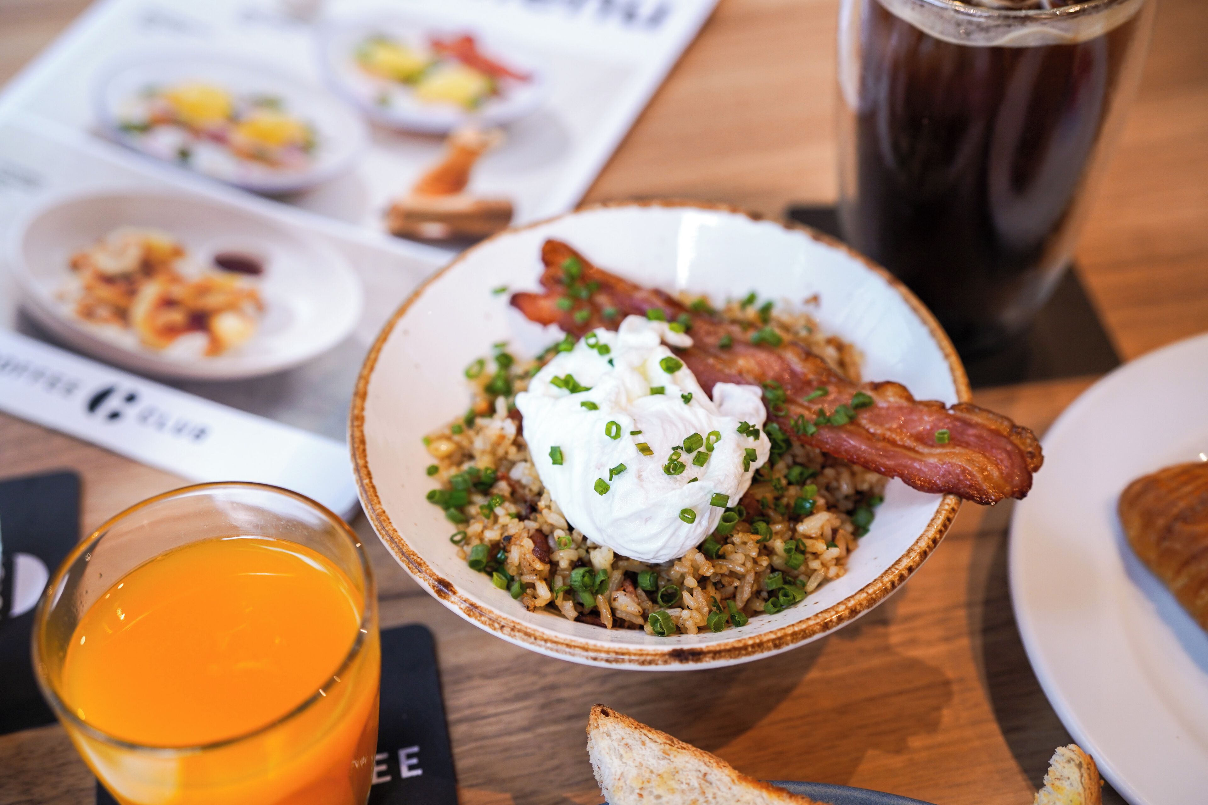 A breakfast setting with a plate of food, a glass of orange juice, and a beverage in the background.