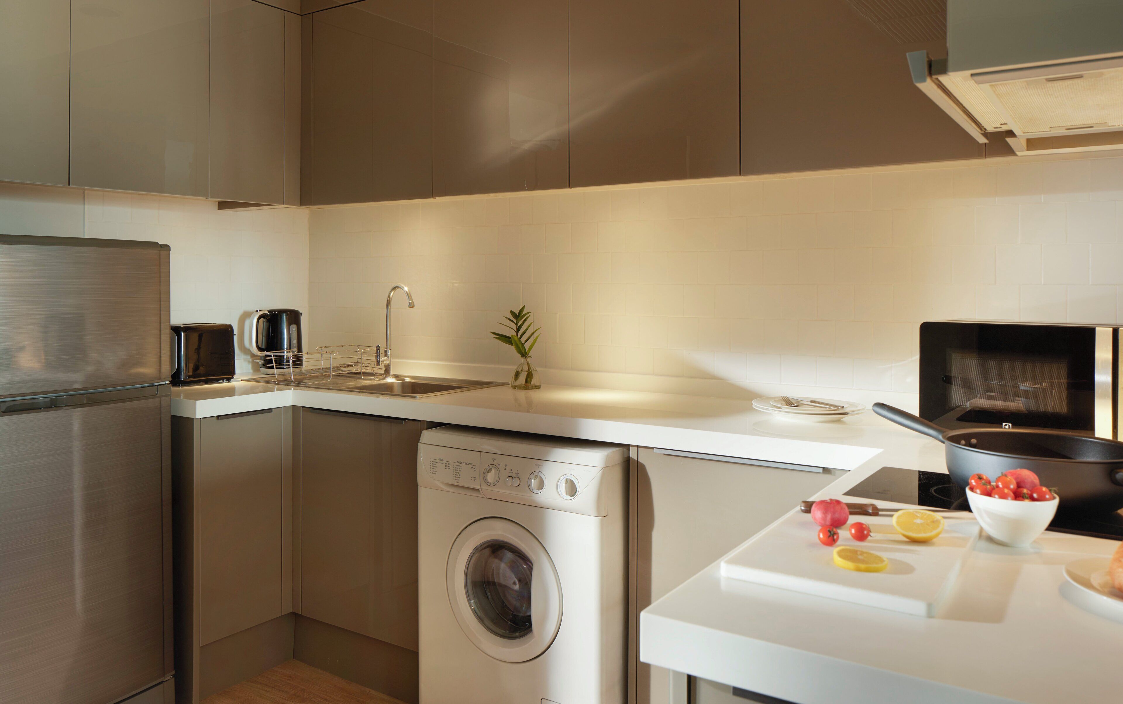 A compact kitchen with a washing machine, a microwave, and a sink.