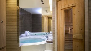 A modern bathroom with a freestanding bathtub, a wooden door, and a large mirror.