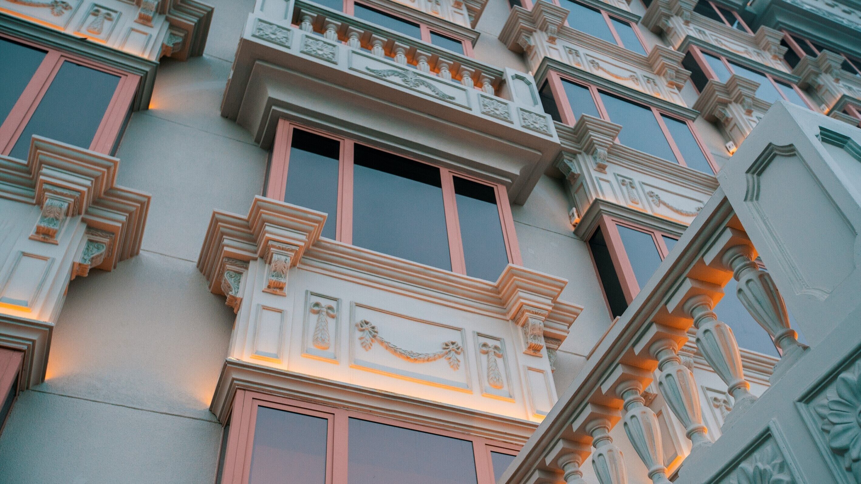A building facade with ornate architectural details, including decorative moldings and a series of windows with shutters.