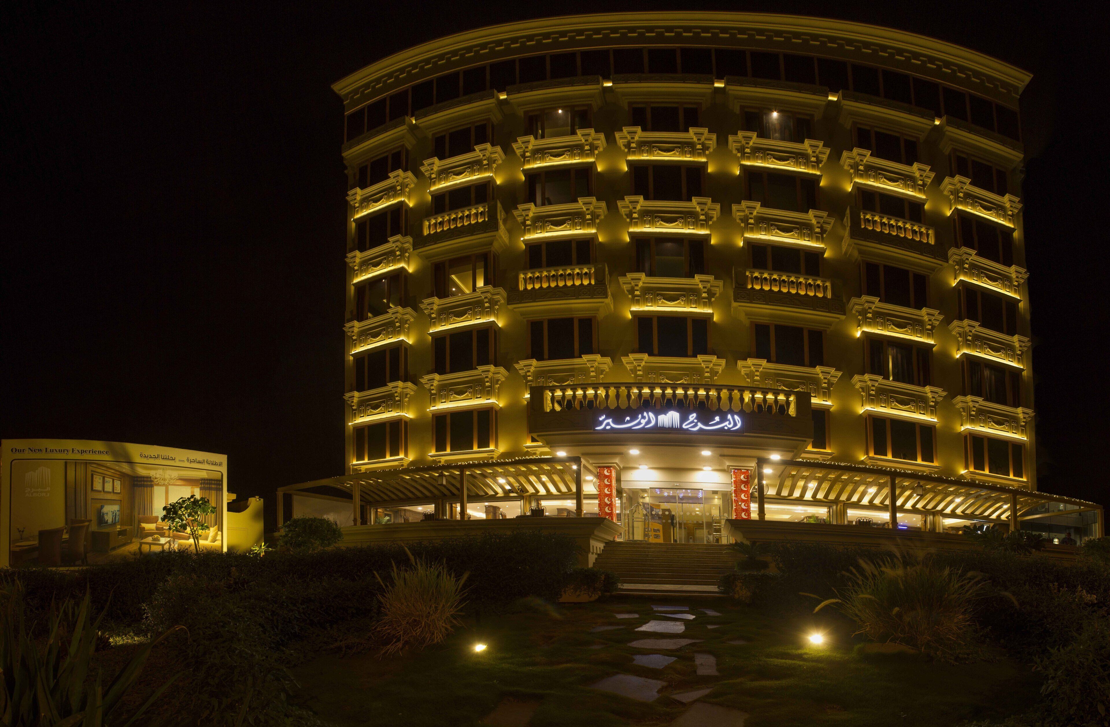 A multi-story hotel with balconies and a well-lit entrance.