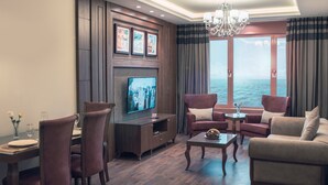 A modern living room with a television, seating, and a view of the sea. - Al-Borg Al-Watheer Serviced Apartments (Jizan)