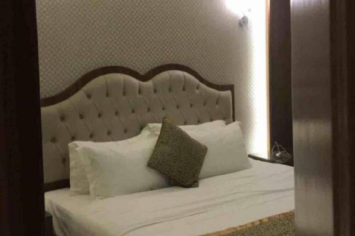 A bedroom with a tufted headboard, a bed with white linens, and a single green pillow.