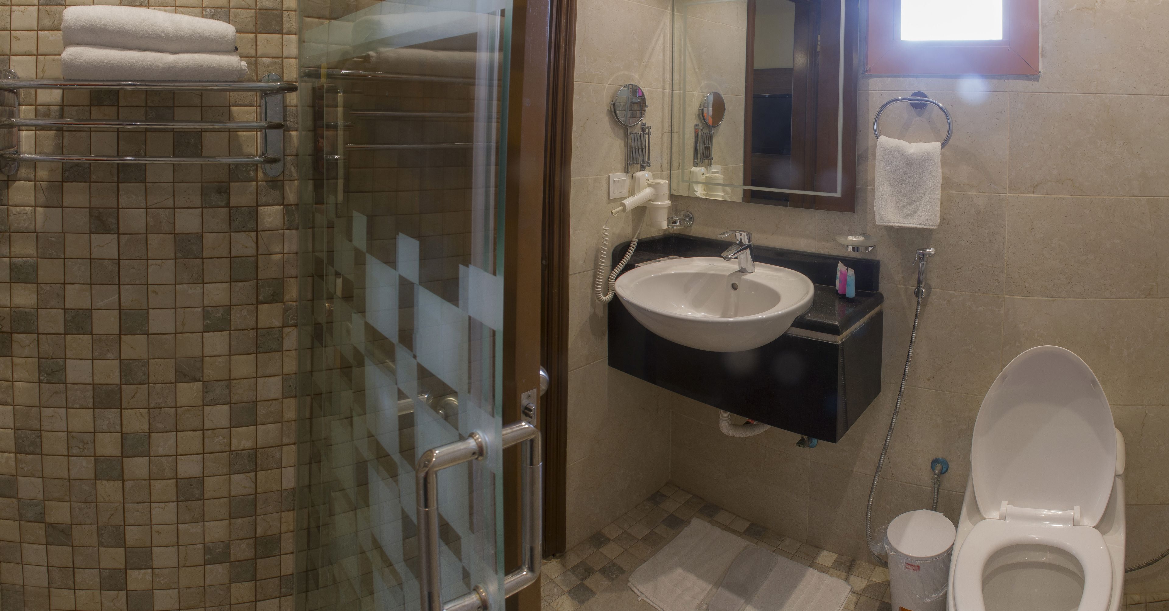 Un baño con cabina de ducha de vidrio, lavabo, inodoro y espejo.