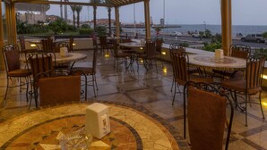 A restaurant with outdoor seating overlooking a coastal view. - Al-Borg Al-Watheer Serviced Apartments (Jizan)
