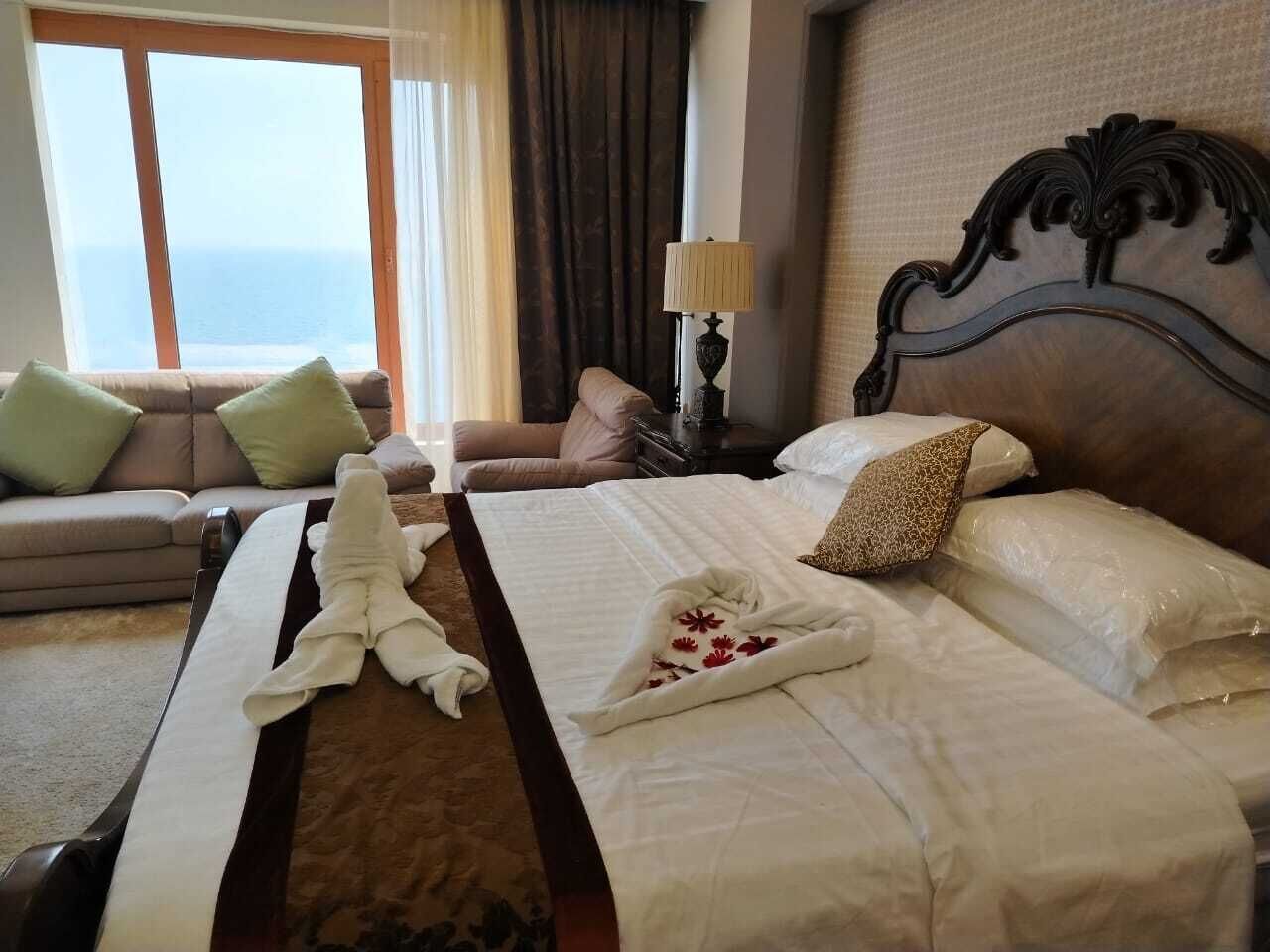 A hotel room with a large bed, a sofa, and a view of the sea.