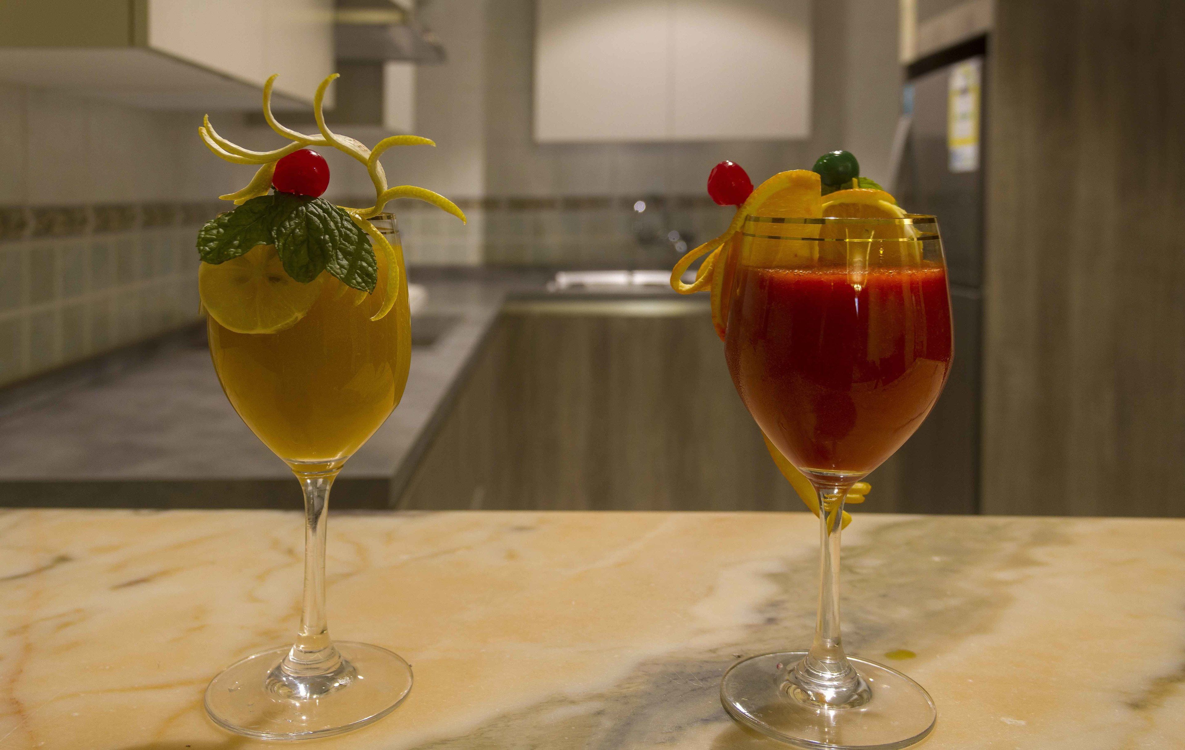 Two elegantly presented cocktails on a marble countertop in a modern kitchen setting.