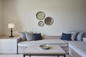 Ein modernes Wohnzimmer mit einer Eckcouch, einem Couchtisch, einer Stehlampe und dekorativen Tellern an der Wand.