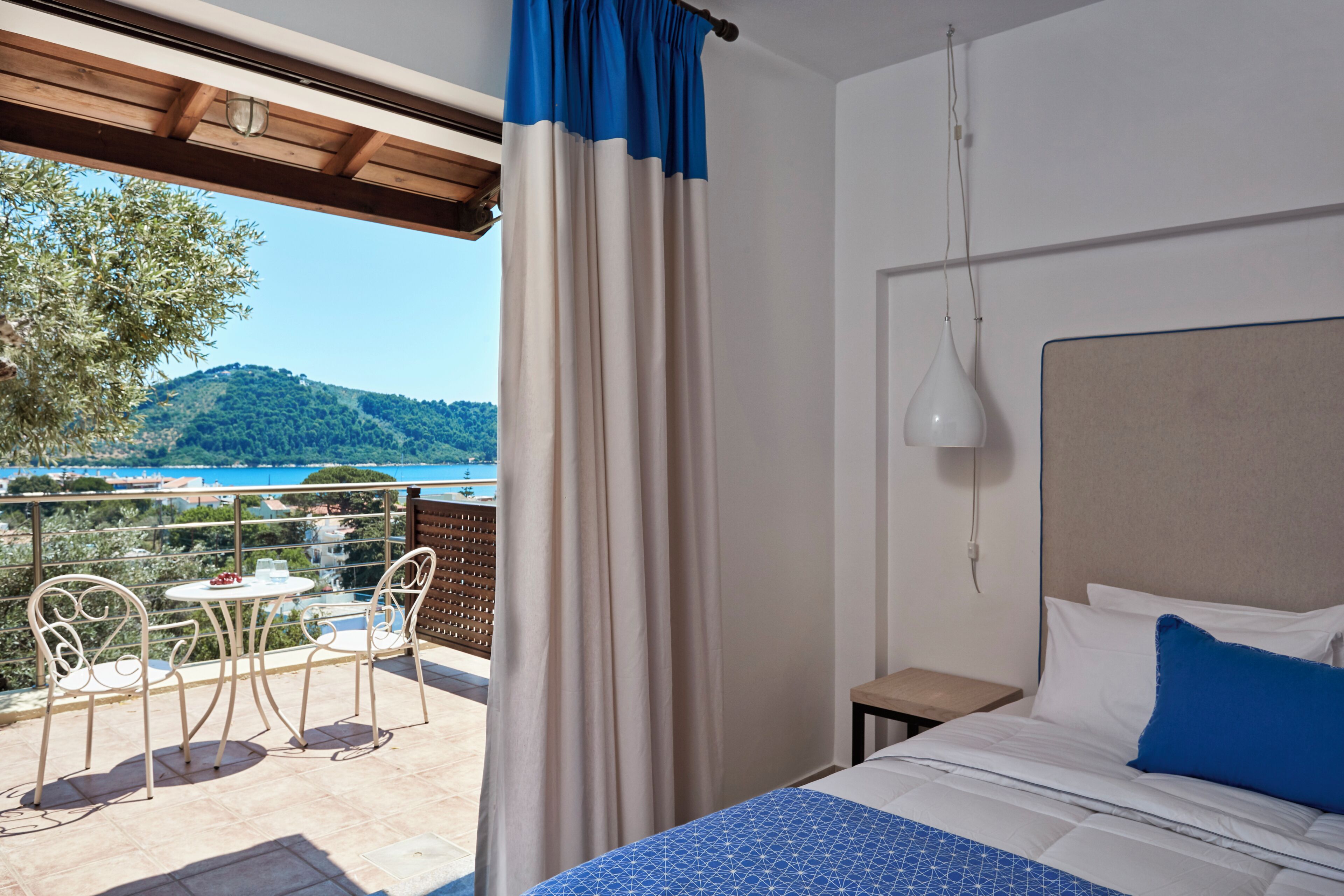 Een hotelkamer met een bed, een tafel met stoelen en uitzicht op een balkon met een tafel en stoelen.