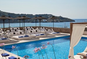 A poolside area with lounge chairs and umbrellas, a clear view of the sea, and a distant hill. - Skiathos Living by GHH (Skiathos)
